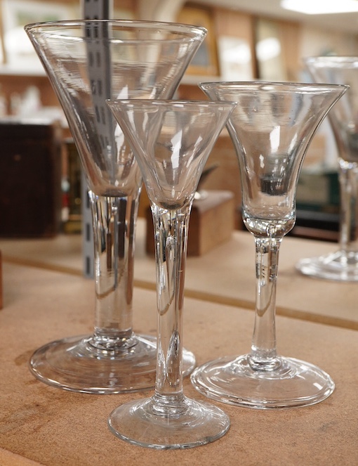 Three late 18th century trumpet glasses, all with plain stems containing tears, tallest 21cm